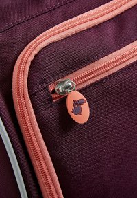 Borsa di tessuto viola con cerniera rosa e un tirazip ovale con un design di uccello blu. La texture appare liscia e resistente.