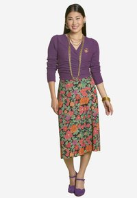 Purple fitted sweater with a v-neck, floral-patterned maxi skirt in black, and purple flat shoes. Gold jewelry accents complete the look.