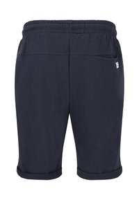 Tummansinisiä puuvillahousuja, joissa on joustava vyötärönauha, käänteet lahkeissa ja takatasku, jossa on pieni tuotemerkki.