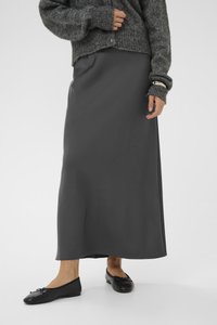 Jupe maxi en gris foncé, faite d'un tissu lisse et fluide ; associée à des ballerines noires avec détail de nœud et un pull en tricot doux.