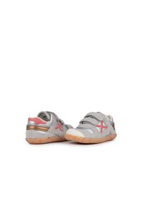 Zapatos de ante gris con acentos rojos, herrajes plateados y una suela texturada. Presentan correas de Velcro para un fácil ajuste y una forma de punta redondeada.
