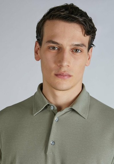 Polo shirt color khaki con colletto, con due bottoni azzurri chiari. Tessuto morbido, design aderente e senza motivi o dettagli visibili.