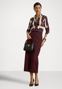 Πολύχρωμο μπλουζάκι με σχέδιο αλυσίδας, μπορντό κουλότ με ψηλή μέση και μικρή μαύρη τσάντα χειρός με χρυσά μεταλλικά στοιχεία και λεπτομέρειες.