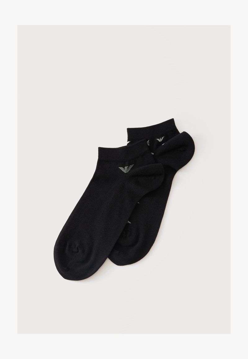 Paire de chaussettes courtes noires avec petit logo blanc sur les bords côtes, posées à plat sur un fond clair.