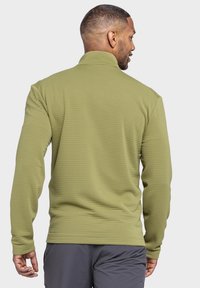 Olivgrüner, langärmeliger Pullover mit hohem Kragen, aus strukturiertem, geripptem Material und einer figurbetonten Passform.