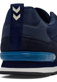 Marinblå idrottssko med en texturerad ovandel, suède detaljer och en vadderad blå sula. Två-chevron detajl på hälen ger visuell intresse.