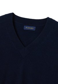 Marineblauwe v-hals trui van zachte stof, met een geribbelde kraag. Merklabel "PIOMBO" zichtbaar in goud op een blauwe achtergrond.
