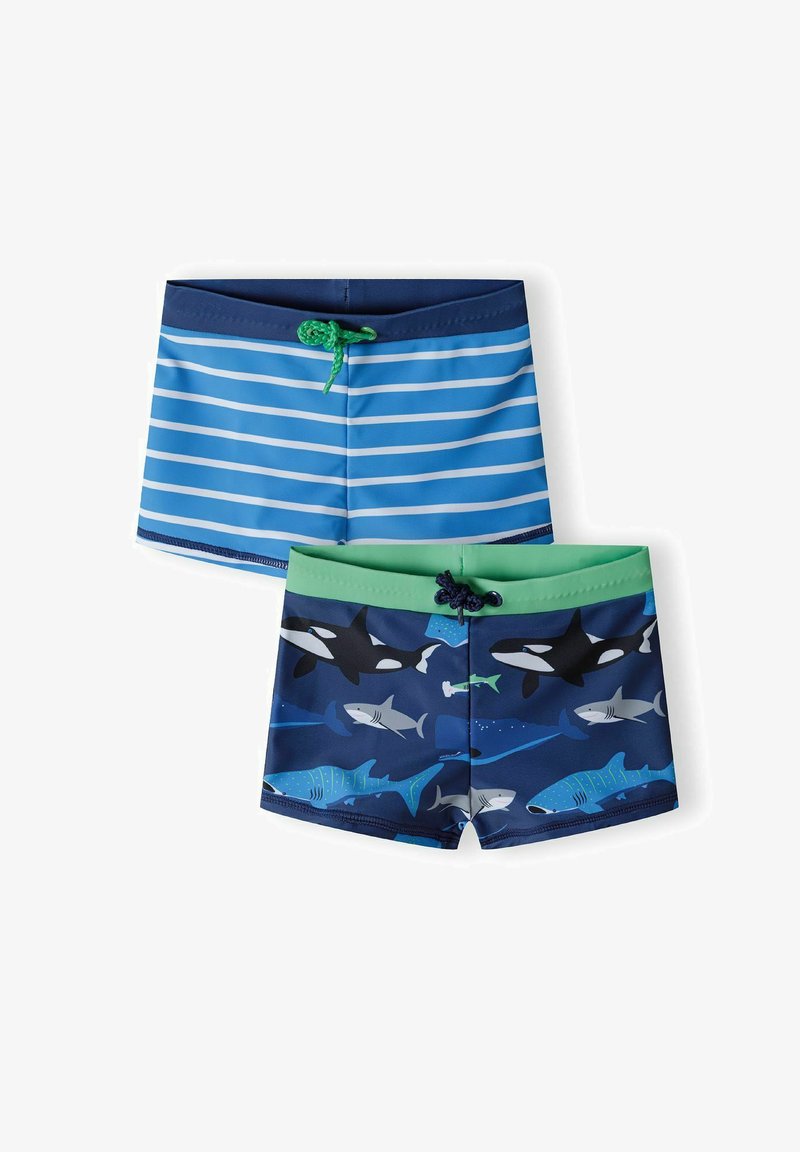 Berniukų maudymosi šortai; vieni turi mėlynas juosteles ir žalią raištį, kiti pasižymi ryklių raštu tamsiai mėlyname fone su žaliu diržu.