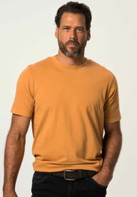 Sennepsgul kortærmet t-shirt i bl�ød bomuld med rund hals. Kombineret med mørke jeans og et brunt bælte.