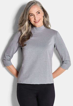 Zilveren driekwart mouwen top met hoge halslijn, met een sprankelende textuur. Gepaard met zwarte onderkleding, omlijnd in een strakke pasvorm.
