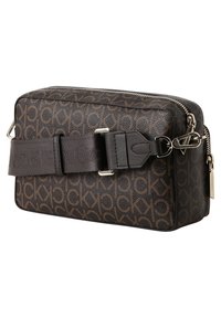 Brązowa, wzorzysta torba ze skóry z zamkiem błyskawicznym, regulowanym paskiem i srebrnymi elementami ozdobnymi. Prostokątny kształt o teksturowanym wykończeniu.