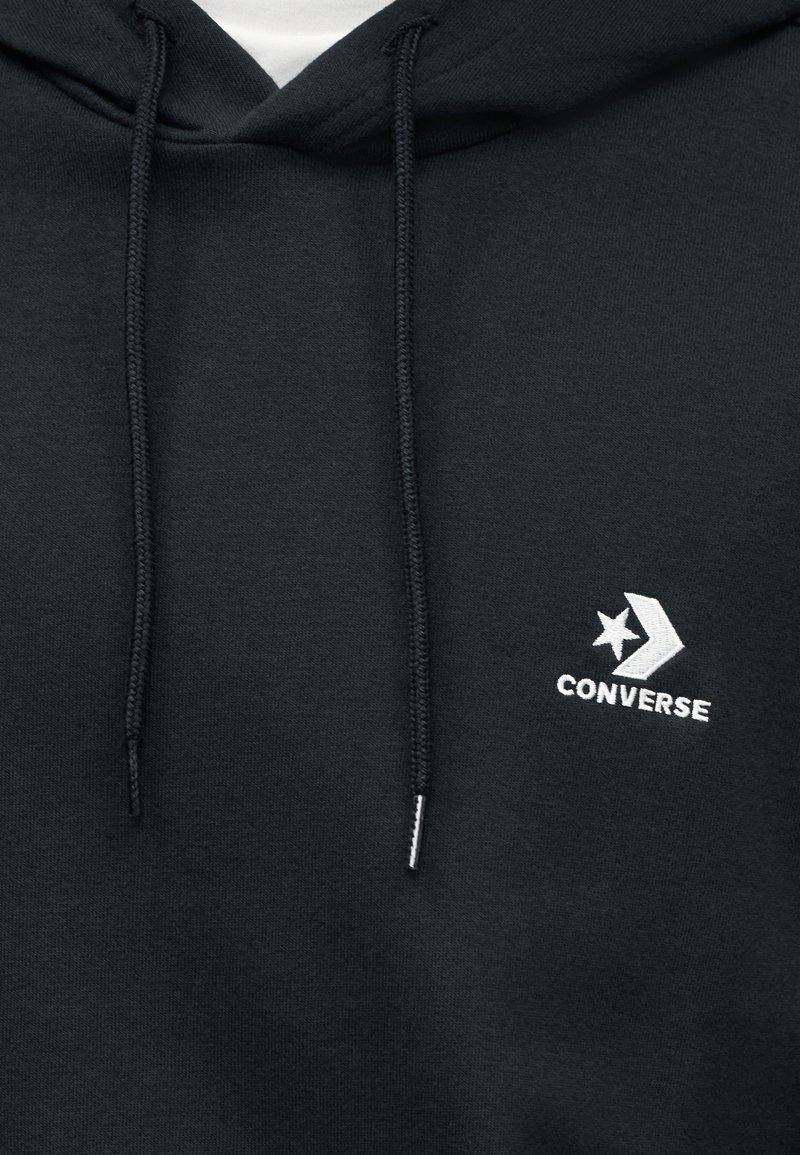Sweat à capuche noir avec cordon de serrage, texture douce et logo "Converse" brodé en blanc avec un motif d'étoile et de flèche.