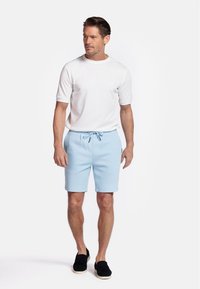 Light blue cotton shorts with adjustable drawstring waistband, paired with a white cotton crewneck t-shirt and black slip-on shoes.