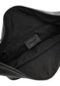 Zwarte leren tas interieur met stoffen voering, een ritssluitingvak en een gestikte merklabel binnenin het hoofdvak.