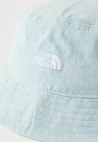 Σκούφος bucket από ανοιχτό μπλε τζιν με λευκό κεντημένο λογότυπο "The North Face" στο μπροστινό μέρος.