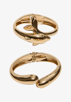To armbånd i guldfarvet tone, den ene med delfin-design og hængsel-lås, den anden en glat, solid bøjle med åben lukning.