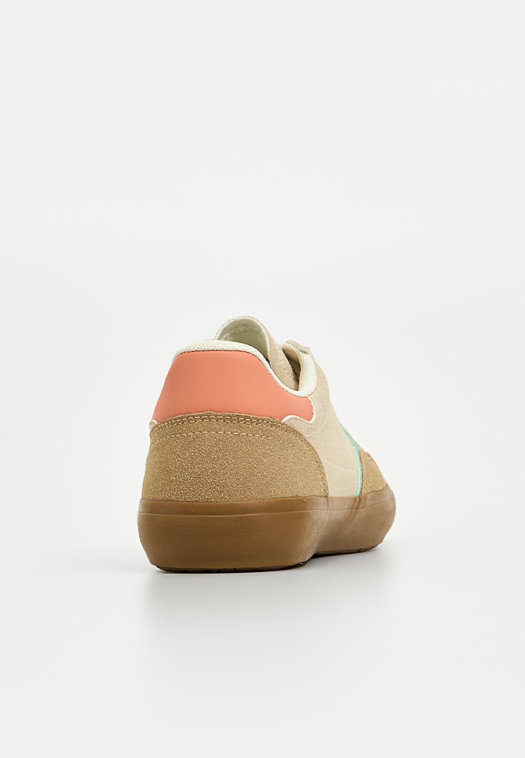 Zapatillas con parte superior de ante beige, detalles texturizados en color tostado, detalle lateral en verde y una tapa de talón en color coral. Suela de goma con un acabado suave.