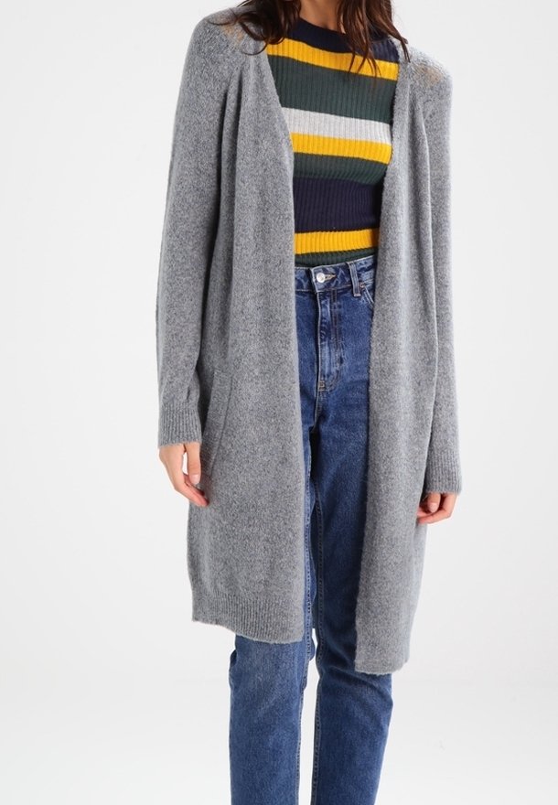 Ljusgrå stickad cardigan med öppen framkant, långa ärmar och ribbade muddar. Bärs över en flerfärgad randig tröja och högmidjade jeans.