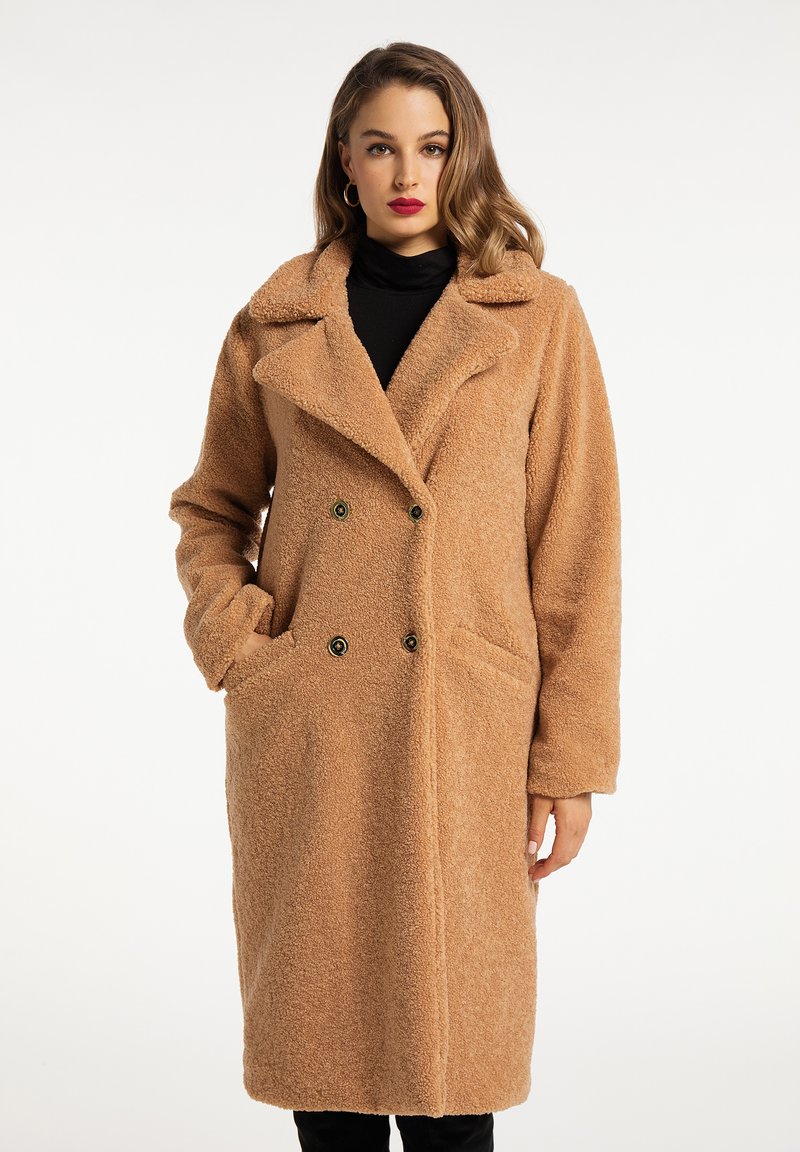 Tan teddy coat with a double-breasted front, notch collar, two front pockets, and textured fabric. Long sleeves with a relaxed fit.
