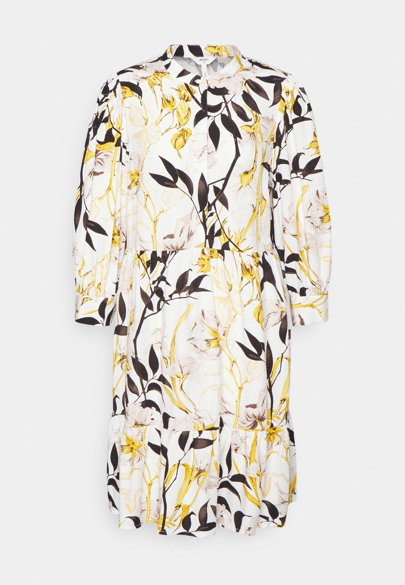 Robe midi blanche à manches longues avec un motif floral jaune et noir, taille froncée et ourlet volanté.