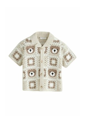 Beżowa koszula z krótkim rękawem, wykonana na szydełku, zapinana na guziki z wzorami twarzy misia w kolorze brązowym i białym oraz gwiazdek na kwadratowych aplikacjach.