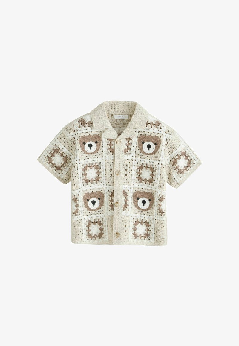 Chemise beige en crochet à manches courtes avec fermeture à boutons, présentant des motifs de visage d'ours marron et blanc ainsi que des étoiles dans des carrés.
