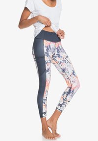 Legginsy z wielokolorowym abstrakcyjnym wzorem w odcieniach różu, pomarańczu i niebieskiego; wysoki stan z jednolitą ciemną kieszenią po boku.