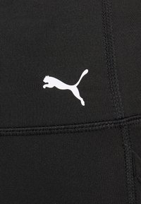 Tejido atlético negro con un logotipo de un gato saltando en blanco. El material es suave con una textura sutil e incluye detalles de costura visibles.