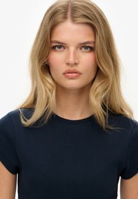 Marineblauwe getailleerde t-shirt met korte mouwen, ronde halslijn en een gestructureerde stof met een subtiele ribbelpatroon.