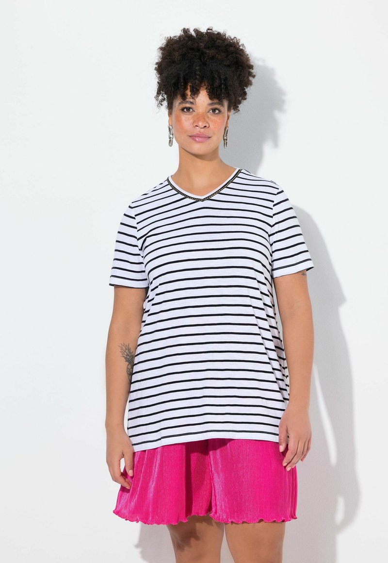 Stribet bomulds t-shirt i hvid og sort, v-hals med perle detaljer, sat sammen med en lys pink plisseret nederdel med bølgede kanter.