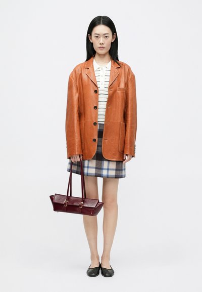 Καφέ δερμάτινο μπουφάν, λευκή τοπ με σχέδια, καρό μίνι φούστα σε μπλε και κρέμα, μπορντό τσάντα με χρυσές λεπτομέρειες, μαύρες εσπαντρίγιες.