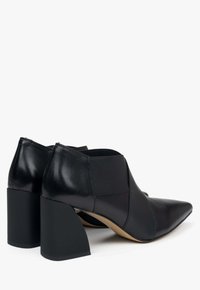 Czarne skórzane botki kostki z wąskim noskiem, elastycznymi bokami i blokowymi obcasami, charakteryzujące się textured wykończeniem i zaokrąglonym fasonem.