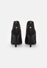 Stivaletti neri in suede con tacco alto, dal design elegante, dotati di una zip sul retro e di un sottile accento silver sul tirante della zip.