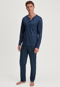 Himmelblaues Langarm-Pyjama-Oberteil mit Tasche und Knopfdetails, kombiniert mit gemusterten navyblauen Hosen. Weicher Stoff, lockerer Schnitt und leicht.