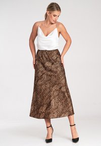 Sukienka z satynowego białego materiału z cienkimi rami ączkami, w zestawieniu z długą spódnicą w brązowy leopardski wzór. Czarne szpilki dopełniają stylizację. Gładka tekstura i zwiewny krój.