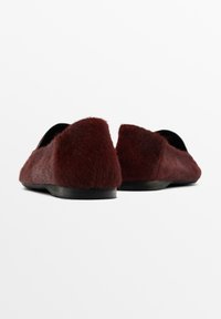 Scarpe basse color borgogna con una texture pelosa e una suola nera bassa, caratterizzate da un retro arrotondato e un design frontale aperto.