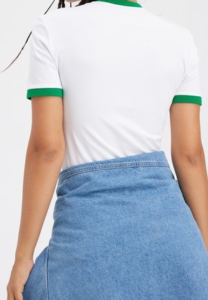 White t-shirt with green trim around the collar and sleeves, paired with a light blue denim skirt. Smooth fabric texture and casual fit.