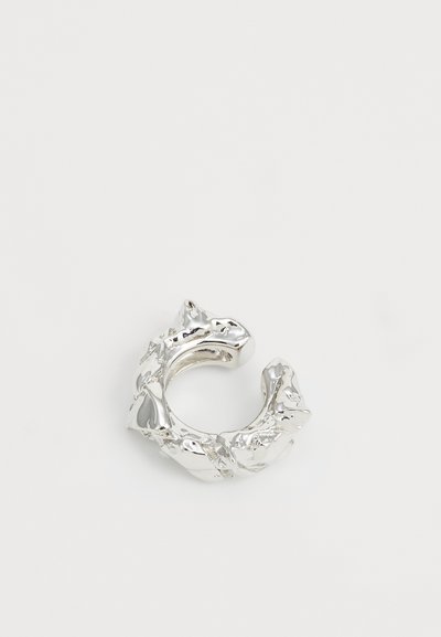 Bague en métal argenté avec une surface texturée et irrégulière, au design de large bande, évoquant des formes inspirées de la nature. Convient à différentes tailles.