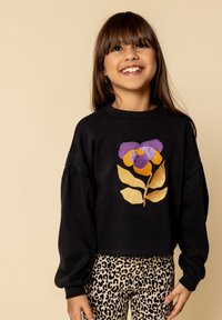 Zwarte cropped sweatshirt met een bloemenpatroon in paars en geel, gecombineerd met legging met luipaardprint. Zacht materiaal, relaxte pasvorm, geribbelde kraag.