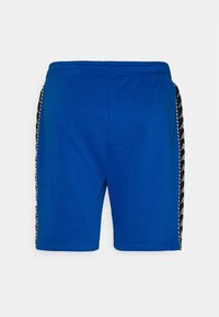 Siniset puuvillahousut, joissa on mustavalkoinen kuvioitu sivupaneeli ja joustava vyötärönauha mukavuutta varten.