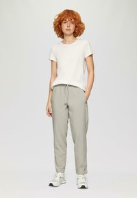 Lichtgrijze tapered broek met een trekkoord in de taille en zijzakken, gecombineerd met een aansluitend wit katoenen T-shirt en witte sneakers.