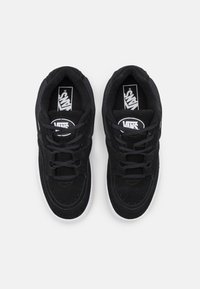 Black suede sneakers with laces, featuring a white rubber sole and Vans logo on the tongue. Textured upper and reinforced stitching details.