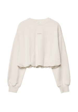 Cream-colored cropped sweatshirt with long sleeves and "studio" printed in small black letters on the chest.