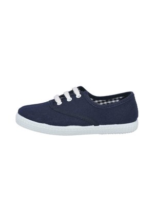 Zapatilla de lona azul marino con suela de goma blanca, punta redonda y tres ojales blancos. El interior presenta un patrón a cuadros en blanco y negro.