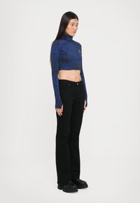 Blue cropped turtleneck sweater with a textured pattern, paired with high-waisted black jeans and black chunky boots.
