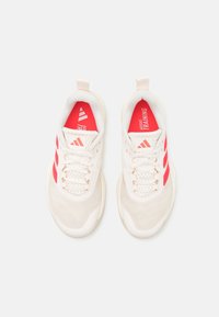 Jasne buty sportowe z siateczkowego materiału, z wyraźnymi różowymi paskami, teksturowaną tkaniną i pętelką z tyłu przy pięcie.