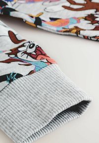 Szary rękaw bluzy z kołnierzem ściąganym, ozdobiony kolorowymi nadrukami postaci z kreskówek. Miękka tekstura materiału z żywymi, wielokolorowymi wzorami.