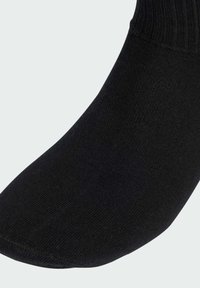 Čierna bavlnená ponožka s rebrovaným vrchným pásom, hladkou textúrou a spevnenou špičkou. Zosilnený dizajn pre pohodlie a prispôsobenie.