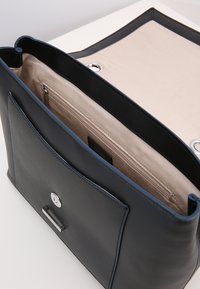 Borsa a tracolla in pelle di colore blu scuro con interno beige. Presenta una chiusura superiore con zipper, hardware silver, e una tasca interna con zipper.
