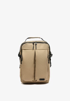 Mochila rectangular beige con dos bolsillos frontales con cremallera, asa superior, hebillas laterales y tiradores de cremallera negros.